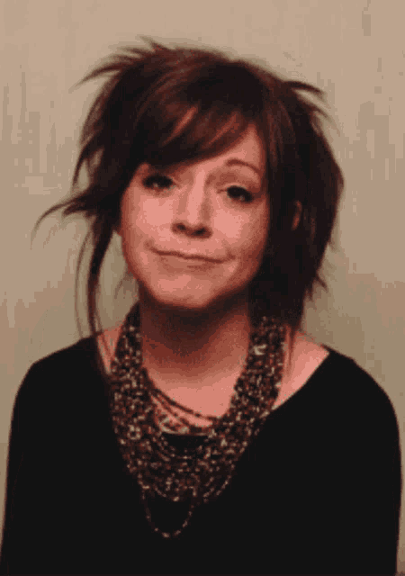 a woman wearing a black shirt and a leopard print necklace smiles
