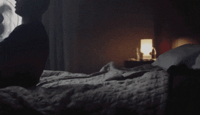 a bed with a fan in the background and a lamp
