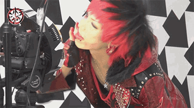 a woman with red hair is kissing a camera with the word mirtek on the bottom