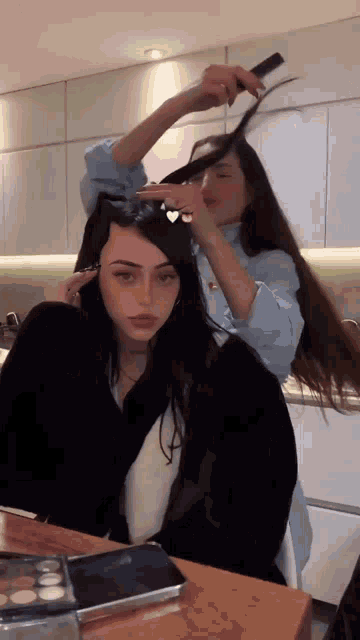 a woman is brushing another woman 's hair while sitting at a table