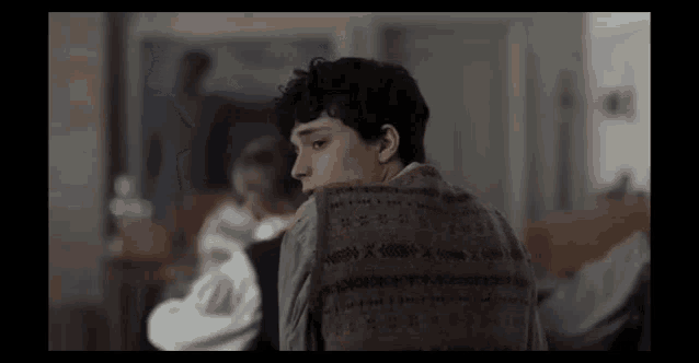 a young man is sitting in a room with his back to the camera and looking at something .