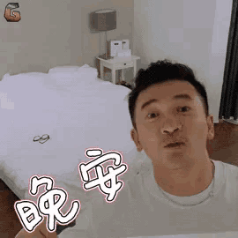 a man is making a funny face in front of a bed in a bedroom