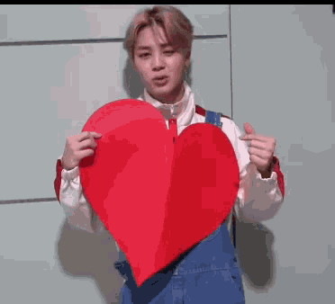 a man is holding a large red heart in his hands .