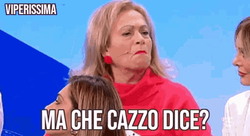 a woman in a red sweater is sitting next to two other women and making a funny face .