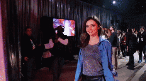 a woman in a blue jacket is standing in front of a crowd of people