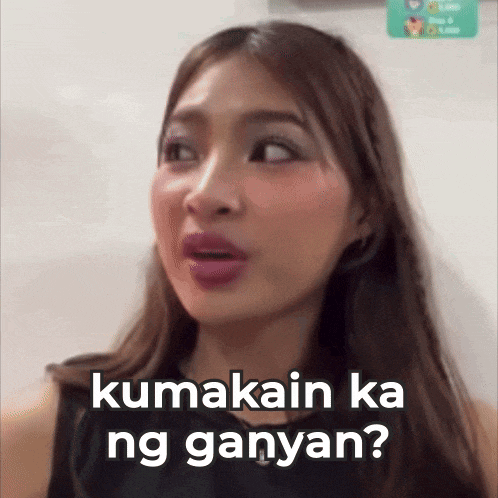 a woman is making a funny face with the words kumakain ka ng ganyan written on the bottom of her face .