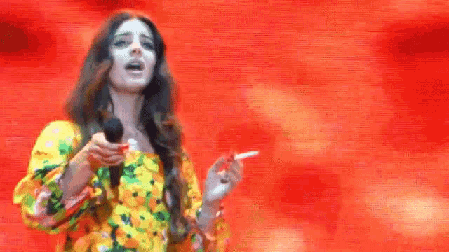 a woman is smoking a cigarette while singing into a microphone on stage .