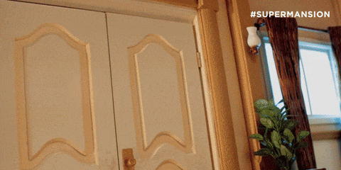 a man in a superhero costume is standing in a doorway with #supermansion written on the door