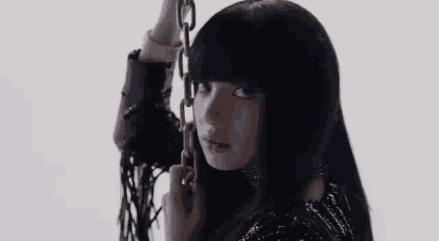 a woman is holding a chain in her hand and looking at the camera .