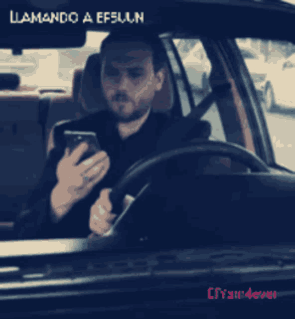 a man sitting in a car looking at his phone