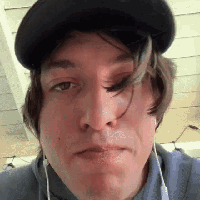 a man wearing a hat and earphones is making a funny face .