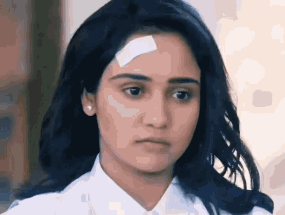 a woman with a bandage on her forehead is looking at the camera .