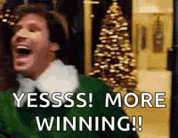 a man in a green sweater is laughing in front of a christmas tree and saying yesss ! more winning .
