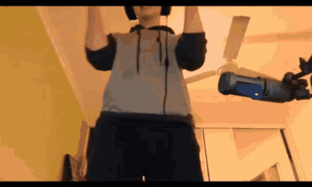a man wearing headphones stands in front of a fan