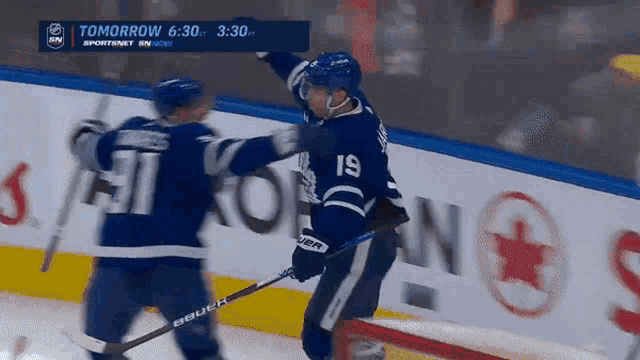 a hockey player with the number 19 on his jersey is hugging another player