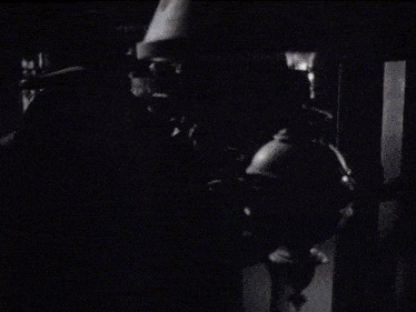 a man in a top hat stands in front of a lamp in a black and white photo