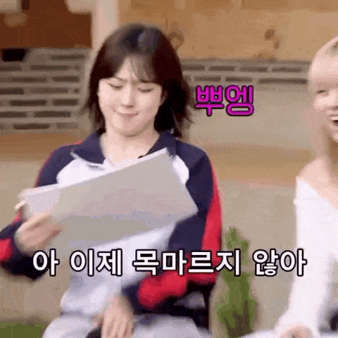 a woman is holding a piece of paper in her hand while another woman looks on .