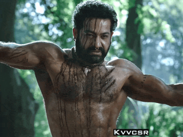 a shirtless man in a forest with the letters kvvcsr on the bottom right