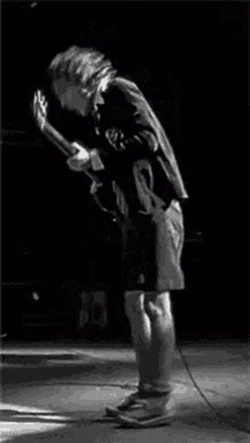 a man is playing an electric guitar on a stage in a black and white photo .