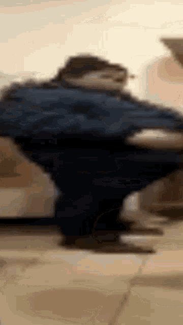 a man in a blue shirt is standing on a tiled floor in a room .