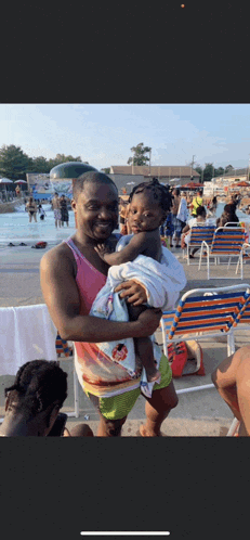 a man is holding a baby in his arms in front of a pool .