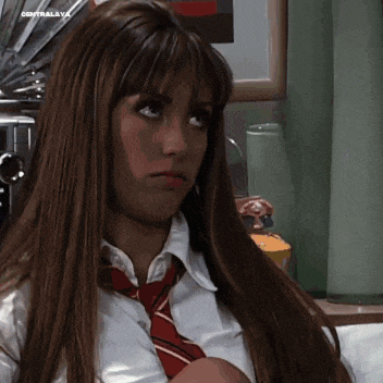 a woman wearing a white shirt and a red tie is sitting on a bed