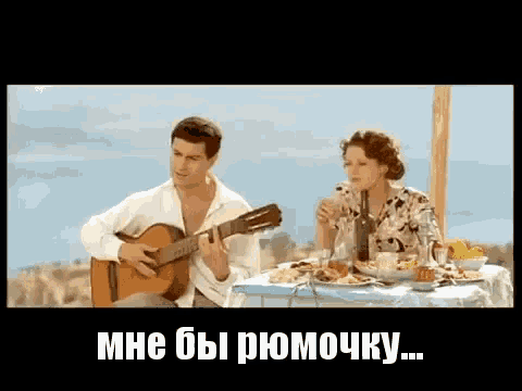 a man is playing a guitar while a woman sits at a table eating