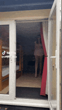 a woman in a pink dress is standing in a doorway with tiktok written on the bottom right