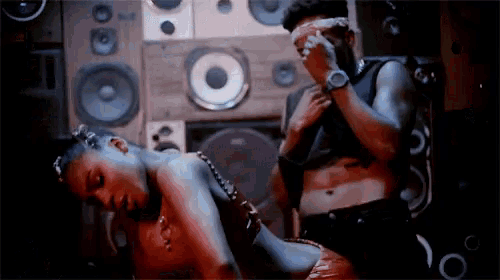 a man and a woman are dancing in front of speakers in a room .