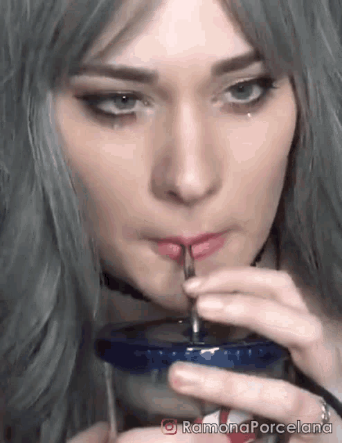 a woman with gray hair is drinking from a plastic cup with a straw ..