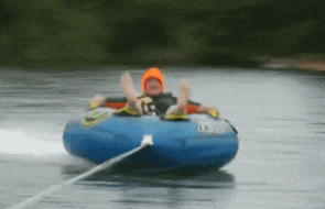 a person in a life jacket is riding a tube in a lake