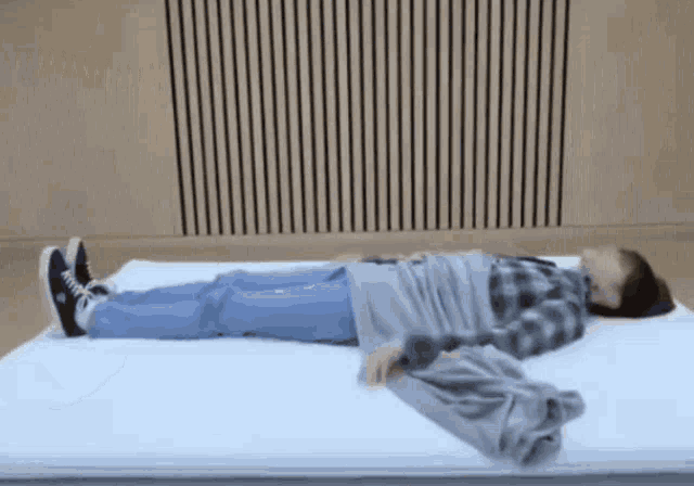 a person wrapped in a blanket is laying on a mattress