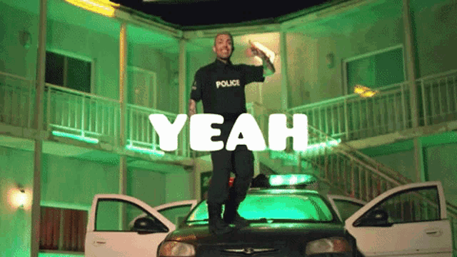 a man in a police uniform is standing on top of a police car with the words " yeah " above him