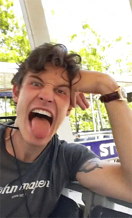 a man with his tongue out wearing a shirt that says john mayer on it