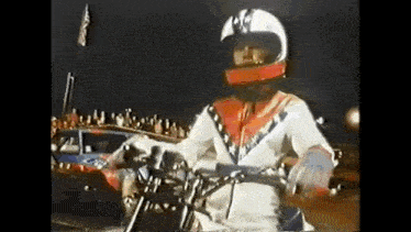 a man wearing a helmet and gloves is riding a motorcycle .