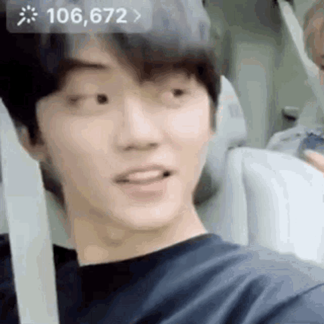 a young man is sitting in a car with his mouth open and looking at the camera .