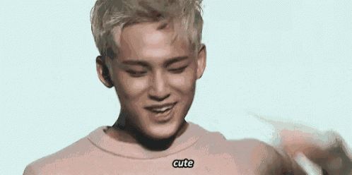 a young man wearing a pink sweater is making a funny face .