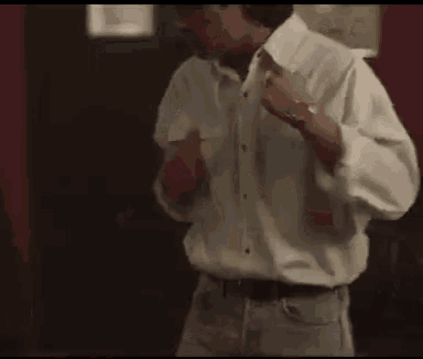 a man in a white shirt is adjusting his shirt collar
