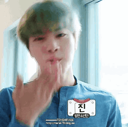 a young man in a blue shirt is making a funny face with his hands .