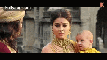 a woman is holding a baby while talking to a man .