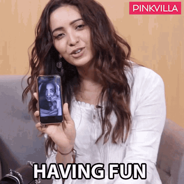a woman is holding a cell phone with the words having fun written on the bottom