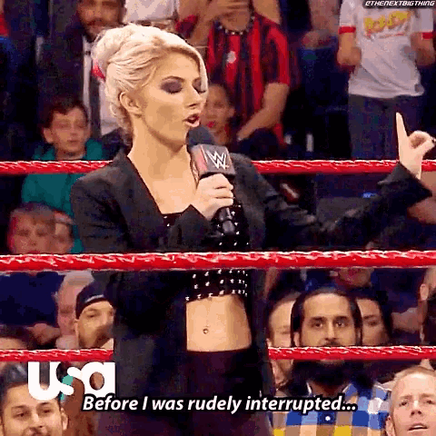 a woman in a wrestling ring is talking into a microphone and says before i was rudely interrupted