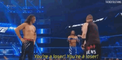 a group of wrestlers are standing in a wrestling ring and one of them is talking to another wrestler .