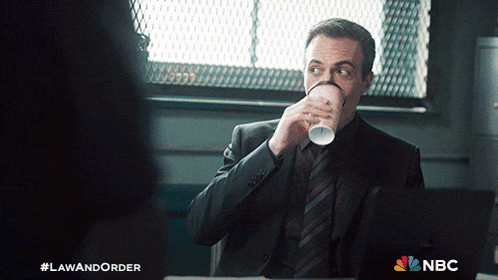 a man in a suit and tie drinking a cup of coffee from a paper cup