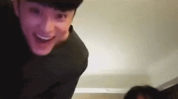 a man is smiling and looking at the camera while standing next to another man in a room .