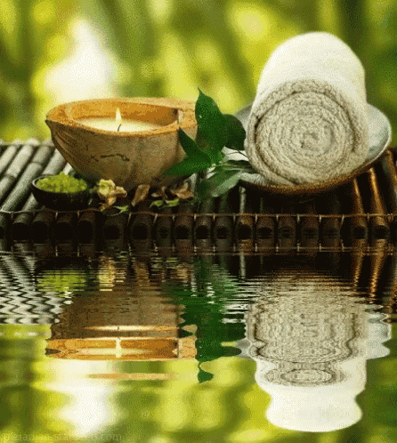 a reflection of a candle and towels in a body of water