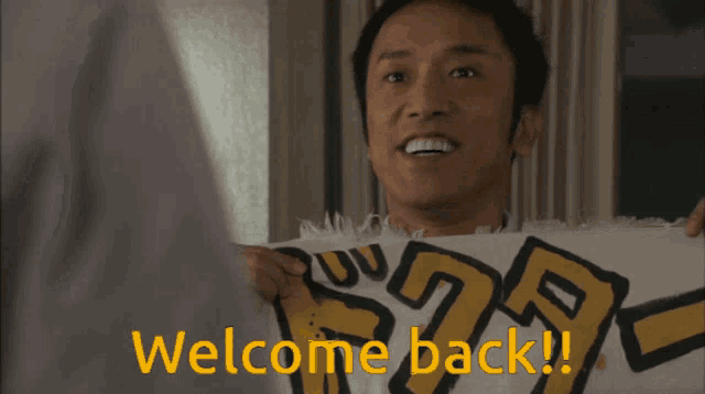 a man holds a sign that says welcome back