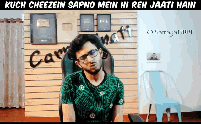 a man sitting in a chair with the words kuch cheezein sapne mein hi reh jaati hain on the bottom