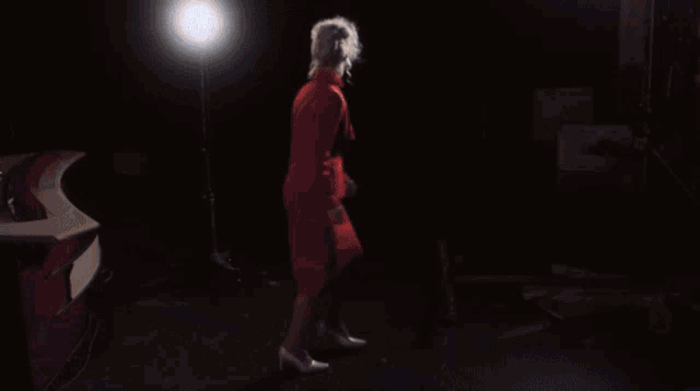 a woman in a red dress is standing in front of a mirror