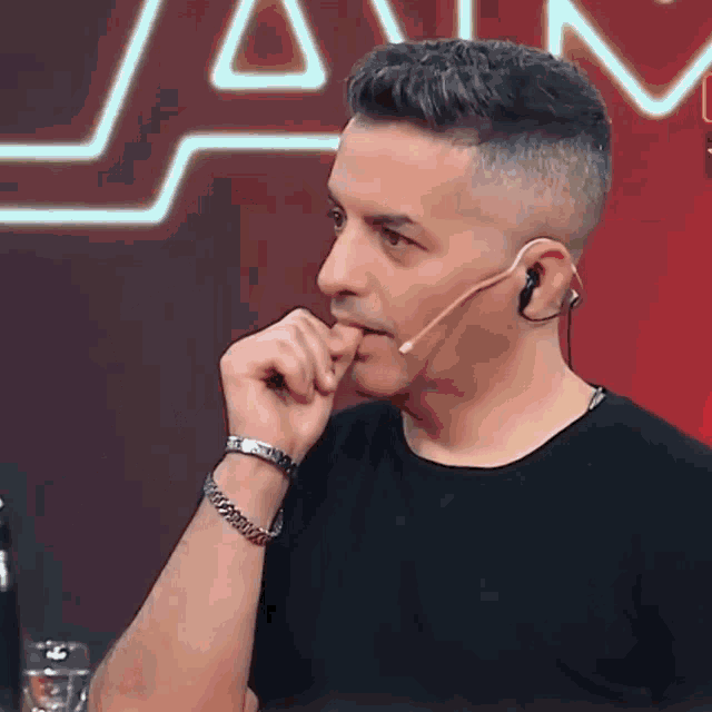 a man wearing a black shirt and ear buds with a microphone in his mouth